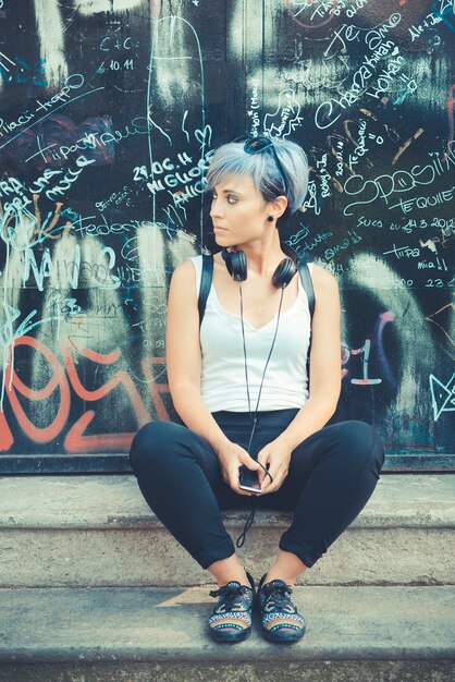 jonge mooie korte blauwe haren hipster vrouw met hoofdtelefoon muziek