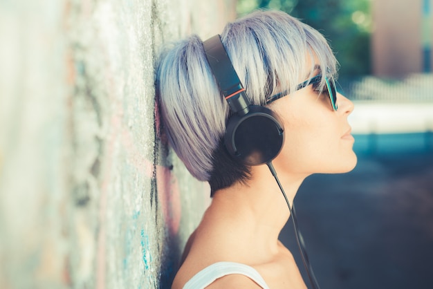 jonge mooie korte blauwe haren hipster vrouw met hoofdtelefoon muziek