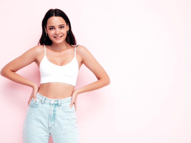 Jonge mooie lachende vrouw in trendy zomerkleren Sexy zorgeloze vrouw poseren in de buurt van roze muur in studio Positieve brunette model plezier en gek vrolijk en gelukkig