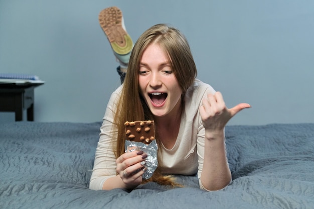 Jonge mooie lachende vrouw met chocolade met hazelnoten