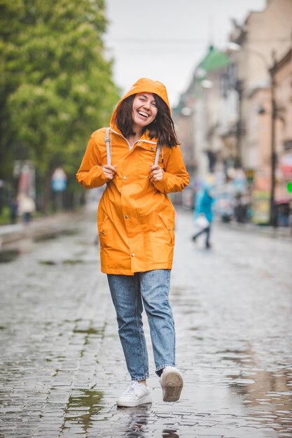 Jonge mooie lachende vrouw portret in regenjas met hood