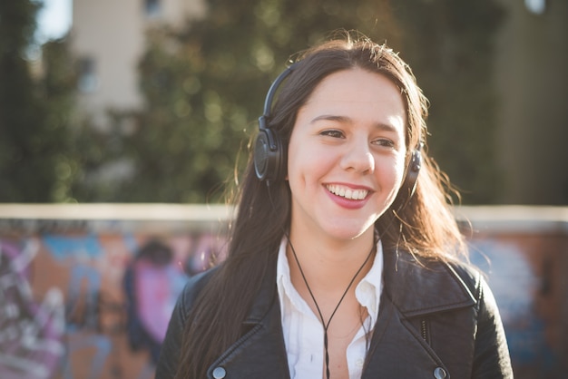 jonge mooie lange haren vrouw luisteren naar muziek in de stad