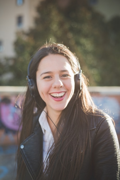 Foto jonge mooie lange haren vrouw luisteren naar muziek in de stad