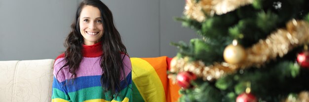 Jonge mooie lesbische vrouw glimlachend en plaatsing op de bank in de buurt van de kerstboom