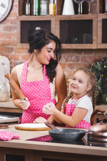 Jonge mooie moeder en haar dochtertje koken samen in de keuken