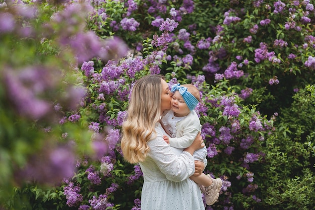 Jonge mooie moeder met dochtertje 15 jaar oud in bloeiende seringen Gelukkige familie in het park Spring