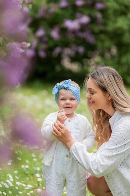 Jonge mooie moeder met dochtertje 15 jaar oud in bloeiende seringen Gelukkige familie in het park Spring