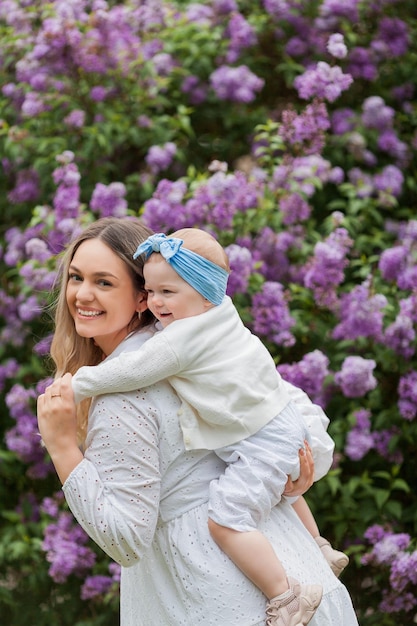 Jonge mooie moeder met dochtertje 15 jaar oud in bloeiende seringen Gelukkige familie in het park Spring