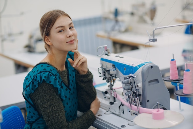 Jonge mooie naaister naait op naaimachine in fabriek.