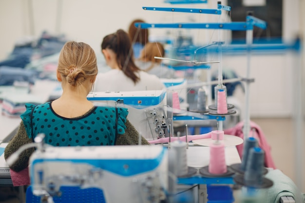 Jonge mooie naaister naait op naaimachine in fabriek.