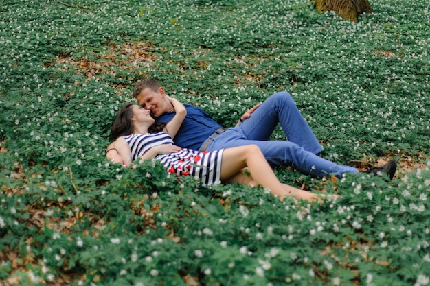 Jonge mooie paar verliefd in het bos. een man en een vrouw liegen en knuffelen in de kleuren van het lentebos. even voor de kus. detailopname. vrije ruimte.