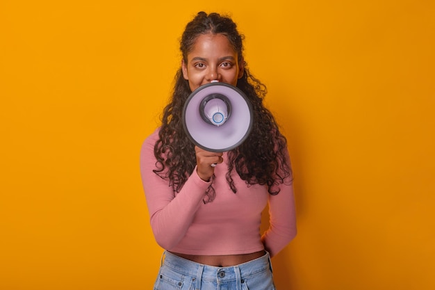 Jonge mooie positieve Indiase vrouw tiener met megafoon in handen