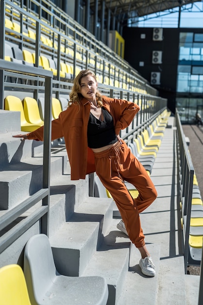 Jonge mooie slanke vrouw in sportkleding ontspannen in de buurt van stoelen in het stadion