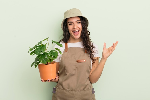 Jonge mooie Spaanse vrouw die blij verrast is en een oplossing of idee van een boer of tuinmanconcept realiseert