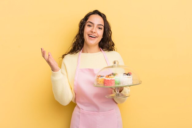 Jonge mooie Spaanse vrouw die blij verrast is en een oplossing of idee voor chef-kok en taarten realiseert