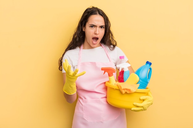 Jonge mooie Spaanse vrouw die boos, geïrriteerd en gefrustreerd kijkt. huishoudelijk werk een concept voor schone producten
