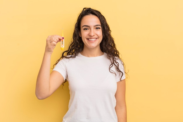 Jonge mooie Spaanse vrouw die gelukkig glimlacht met een hand op heup en zeker thermometerconcept