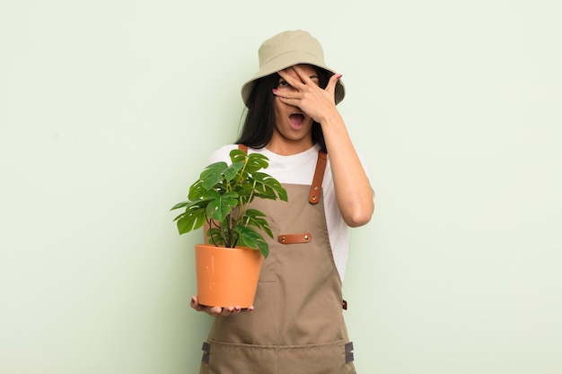 Jonge mooie Spaanse vrouw die geschokt, bang of doodsbang kijkt met een handboer of tuinmanconcept