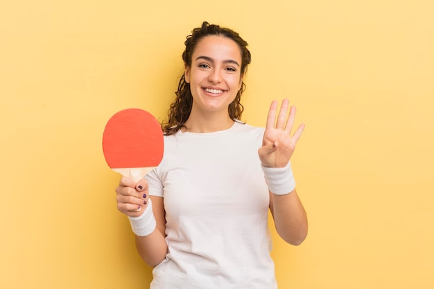 Jonge mooie Spaanse vrouw die lacht en er vriendelijk uitziet met nummer vier pingpongconcept