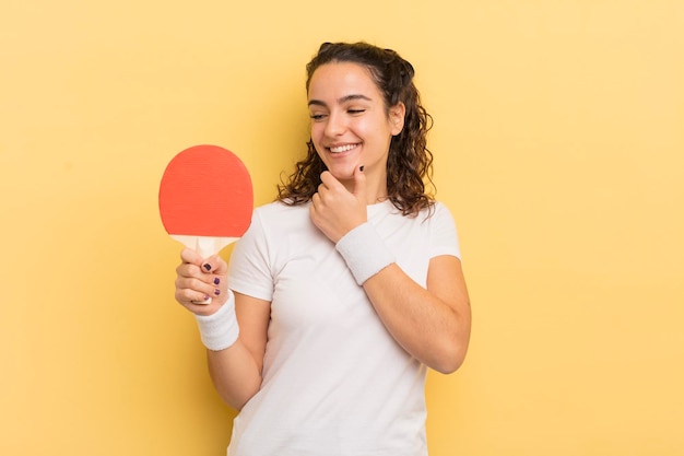 Jonge mooie Spaanse vrouw die lacht met een gelukkige zelfverzekerde uitdrukking met de hand op het kin ping pong concept