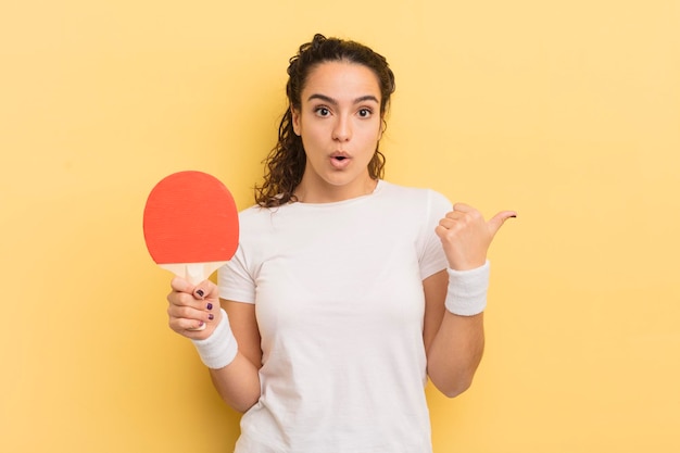 Foto jonge mooie spaanse vrouw die verbaasd kijkt in ongeloof pingpongconcept