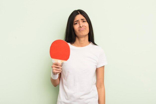 Jonge mooie Spaanse vrouw die verdrietig en zeurt met een ongelukkige blik en huilend pingpongconcept