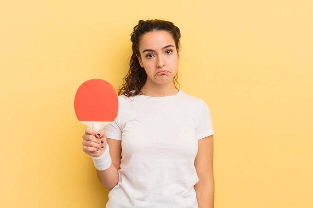 Jonge mooie Spaanse vrouw die verdrietig en zeurt met een ongelukkige blik en huilend pingpongconcept