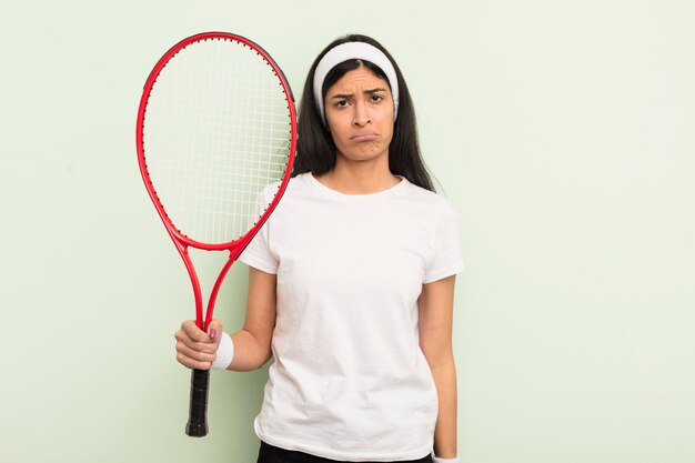 Jonge mooie Spaanse vrouw die verdrietig en zeurt met een ongelukkige blik en huilend tennisconcept