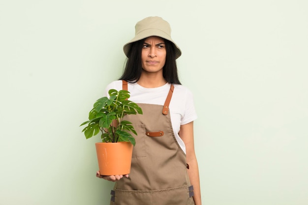 Jonge, mooie Spaanse vrouw die verdrietig van streek of boos is en naar het concept van de zijboer of tuinman kijkt