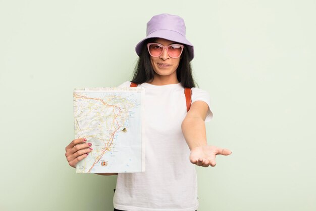 Jonge mooie Spaanse vrouw die vrolijk lacht met vriendelijk en een concept toerist en kaartconcept aanbiedt en toont
