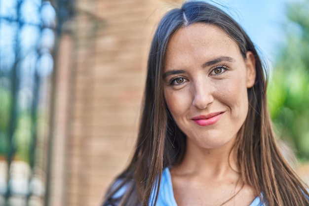 Jonge mooie spaanse vrouw glimlachend zelfverzekerd staande op straat