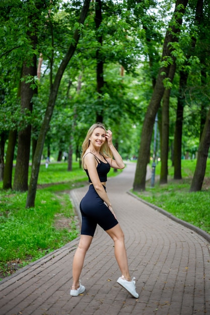 Jonge mooie sportieve blonde vrouw in een zwart T-shirt en in zwarte strakke sportbroek