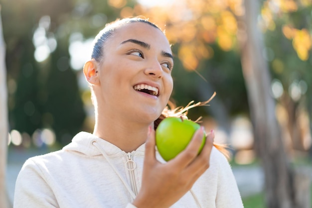 Jonge mooie sportvrouw die een appel met gelukkige uitdrukking houdt