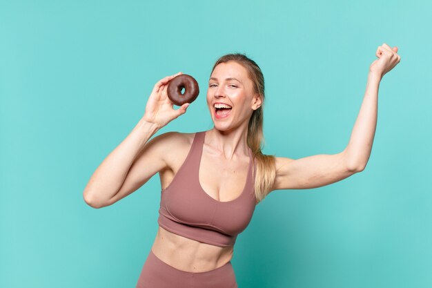 Jonge mooie sportvrouw die een overwinning succesvol viert en een donut vasthoudt