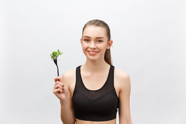 Jonge mooie sportvrouw die salade eet