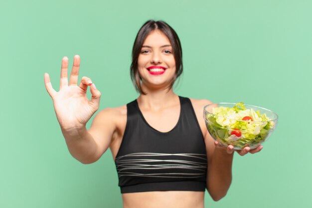 Jonge mooie sportvrouw gelukkige uitdrukking en met een salade