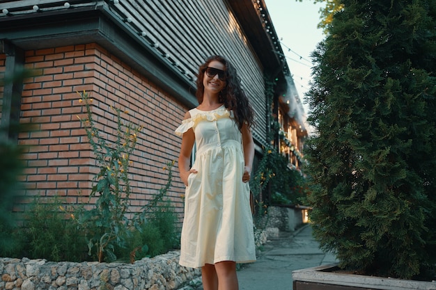Jonge mooie stijlvolle vrouw in zonnebril lopen op een zomerjurk