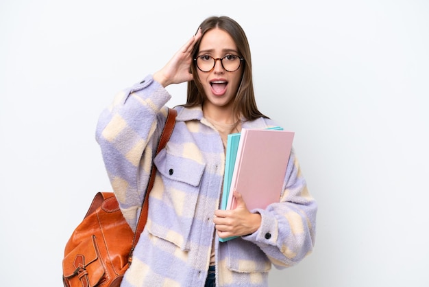 Jonge mooie studentenvrouw die op witte achtergrond met verrassingsuitdrukking wordt geïsoleerd