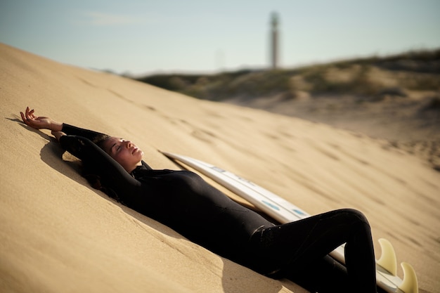 Jonge mooie surfer vrouw op het strand bij zonsondergang