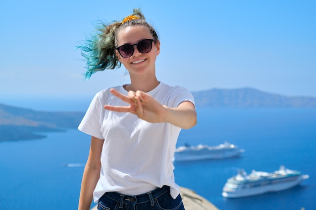 Jonge mooie tiener meisje toeristische poseren glimlachend, achtergrond zomer zonnige schilderachtige zee landschap met witte cruiseschepen in de Egeïsche Zee op het beroemde Griekse eiland Santorini