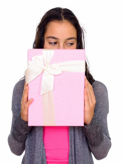 jonge mooie tiener meisje verstopt achter geschenkdoos geïsoleerd tegen witte ruimte