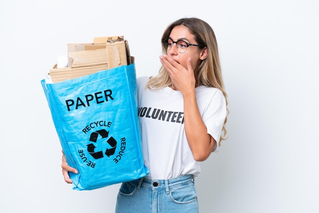 Jonge mooie uruguayaanse vrouw met een recyclingzak vol papier om te recyclen geïsoleerd op witte chroma achtergrond met verbazing en geschokte gezichtsuitdrukking