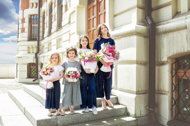 Jonge mooie volwassen moeder en haar kleine vrolijke en gelukkige dochters met boeketten bloemen