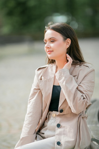 Jonge mooie vrouw 19 jaar oud in stijlvolle kleding Model met donker haar in vrijetijdskleding loopt door de lente bloeiende stad Warm