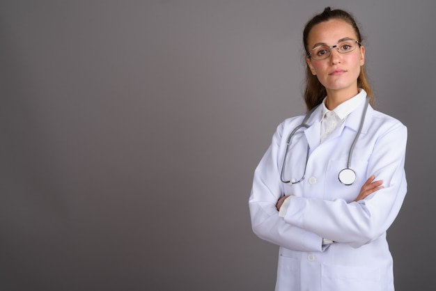 Jonge mooie vrouw arts tegen een grijze achtergrond