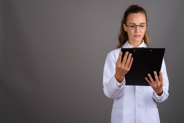 Jonge mooie vrouw arts tegen een grijze achtergrond