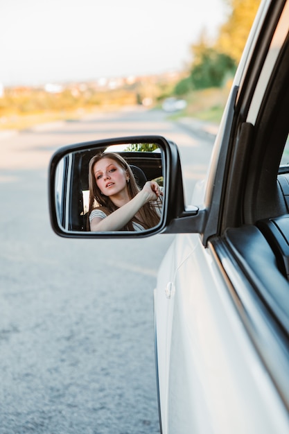 Jonge mooie vrouw auto rijden op zonsondergang. warme zonnige dag