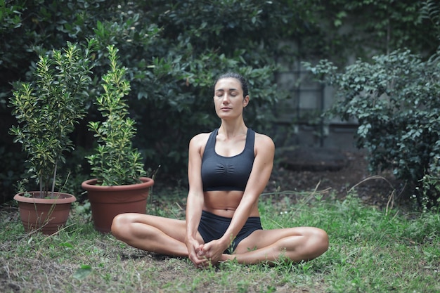 jonge mooie vrouw beoefent yoga in een tuin