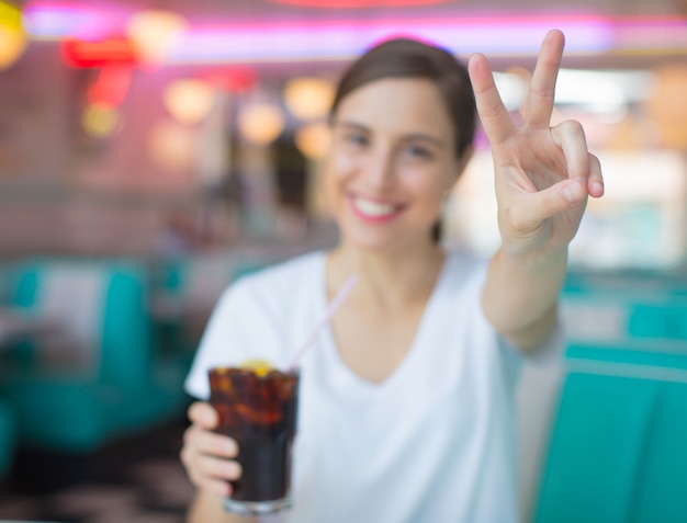 jonge mooie vrouw blij en tevreden een cola drinken in een Amerikaans restaurant voor het diner