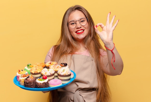 Jonge mooie vrouw. blije en verraste uitdrukking bakker met cupcakes